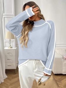 Détail d'un pull en maille bleu clair avec des rayures blanches contrastées sur les coutures