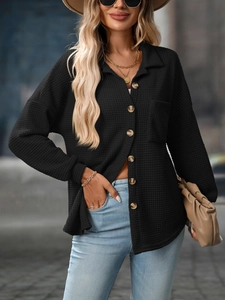 Close-up of black waffle knit texture on a loose casual shirt with buttons and front pocket