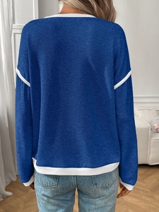 Detail view of the back of a navy knit sweater with white trim and ribbed texture