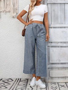 Dettaglio dei pantaloni a righe blu a vita alta e del completo estivo crop top bianco
