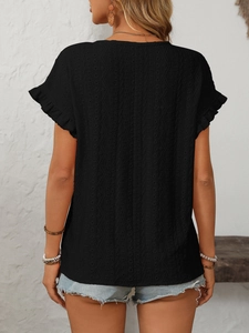 Détail du tissu brodé ajouré noir et des manches à volants sur ce t-shirt femme