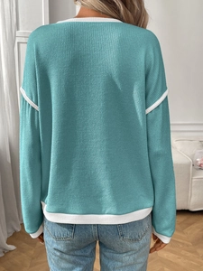 Close-up of turquoise knit sweater with white contrast trim and vertical texture details