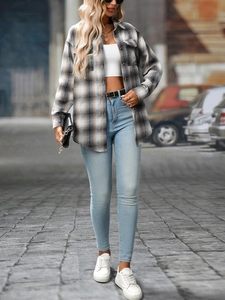 Outdoor street style outfit with plaid brushed shirt, crop top, and slim blue jeans