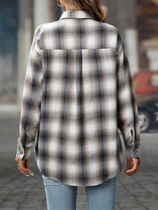 Back view of women's oversized plaid flannel shirt with a curved hem in a street setting