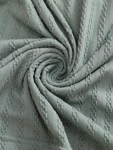 Macro shot of light bean green knitted fabric featuring intricate cable and ribbed texture
