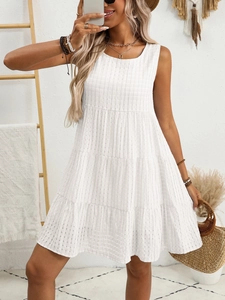 Detail of white sleeveless tiered dress featuring subtle plaid texture and flowy cotton fabric