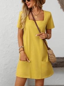 Detail view of ginger yellow square neck dress showing soft cotton texture and front pockets