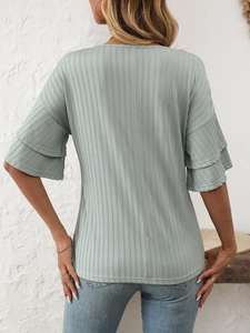 Detailed macro view of light green ribbed fabric and layered ruffle sleeves on women's top