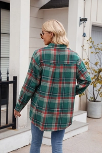 Rear view of a loose-fit green plaid flannel shirt for women on a model outdoors