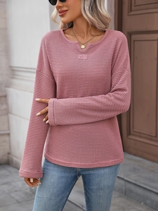 Dettaglio maglia rosa a maniche lunghe in maglia a nido d'ape con scollo a V