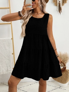 Detail of black sleeveless dress featuring checkered texture and tiered A-line skirt