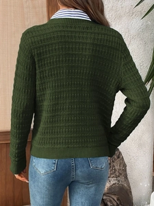 Detail of dark green waffle knit cardigan with elegant ribbed cuffs and hem texture