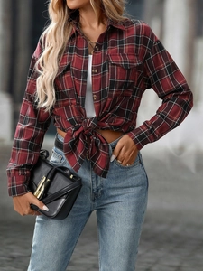 Detail of red and black plaid shirt featuring front pockets and classic button closure