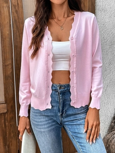 Detail of pink ruffled knit cardigan with ice silk fabric and gold necklace accent