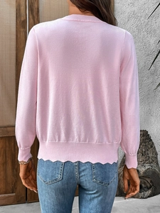 Detail of light pink knitted cardigan featuring unique wavy hem and fine knit texture