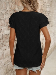 Detail of black hollow mesh T-shirt with double layer ruffle sleeves on brick background