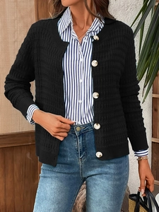 Close-up of black waffle knit cardigan featuring decorative golden embossed buttons