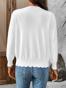 Detailed back view of white knit cardigan showing elegant scalloped hem and ribbed cuffs