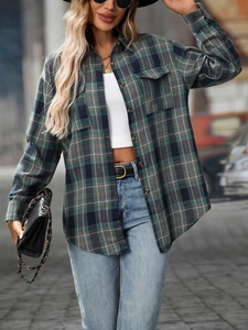 Detail of loose plaid shirt featuring dark green and navy pattern with flap pockets