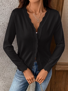 Detail of scalloped edge and matching buttons on a black V-neck knitted cardigan