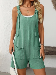 Dettaglio tutina in maglia a righe verdi con spalline a fiocco e grandi tasche frontali