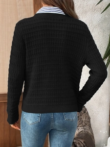 Close-up back view of black knitted cardigan featuring textured waffle pattern and ribbed cuffs