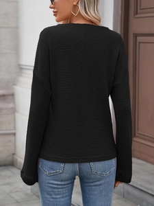 Dettaglio posteriore di una maglia nera a maniche lunghe in maglia a nido d'ape e girocollo