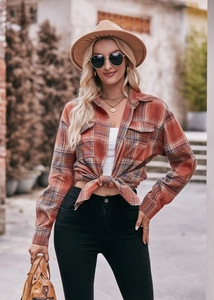 Detail of orange plaid flannel shirt featuring classic collar and symmetrical chest pockets