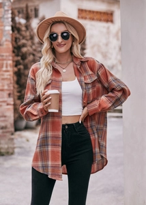 Outdoor street style shot of women's oversized plaid flannel shirt in orange and blue