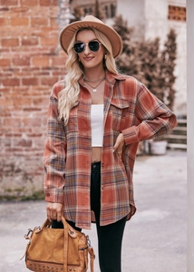 Detail of oversized plaid shirt texture and button closure in warm autumn colors