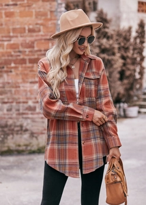 Detail of oversized orange plaid flannel shirt featuring dual chest pockets and retro texture
