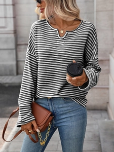 Dettaglio del tessuto a maglia nido d'ape su maglia a righe bianche e nere con scollo a V