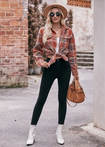 Detail of an oversized plaid shirt tied at the waist with black skinny jeans and boots