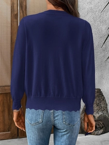 Detail of navy blue knit cardigan featuring ribbed cuffs and wavy hem decoration
