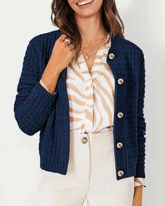 Detail of navy knit cardigan featuring waffle texture and elegant gold buttons