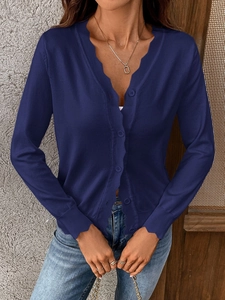 Detailed close-up of navy blue knit cardigan featuring elegant scalloped edges and buttons
