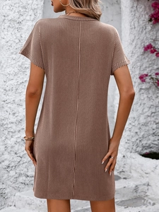 Back view of brown and white striped summer dress against white wall with pink flowers