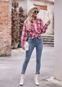 Detail of red plaid flannel shirt tied at the waist with high waist button fly jeans