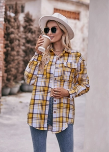 Close-up of a women's yellow and white plaid oversized shirt with flap pockets and buttons