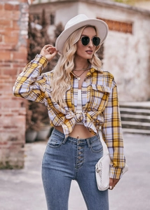Detail of yellow and purple plaid oversize shirt knotted at the waist with denim jeans