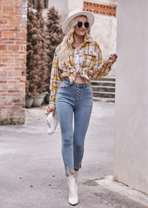 Close-up of oversized yellow plaid shirt knotted at the waist with blue denim jeans