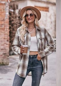 Detail of oversized plaid shacket with brown and green patterns on outdoor brick wall