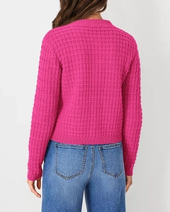 Detail view of pink knit sweater featuring textured popcorn stitch and ribbed collar