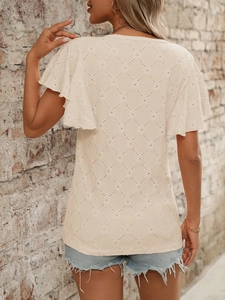 Dettaglio top beige in maglia crochet con motivi traforati e maniche a volant