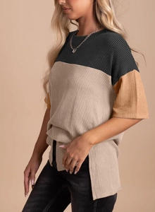 Detailed close-up of color-block ribbed knit top with side slit and texture