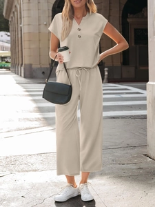 Detail of a beige two-piece lounge set with short sleeve button top and wide-leg pants