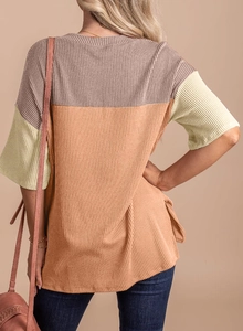 Back view of a ribbed knit t-shirt featuring color block panels in purple, orange, and beige