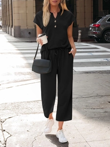 Detail of black two-piece set with V-neck button top and high waist drawstring trousers