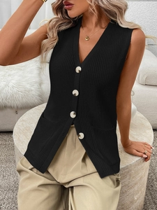 Detail of black knit vest featuring V-neckline, marble buttons and side pockets