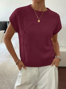 Dettaglio del top in maglia bordeaux con ricamo floreale 3D testurizzato sul lato laterale